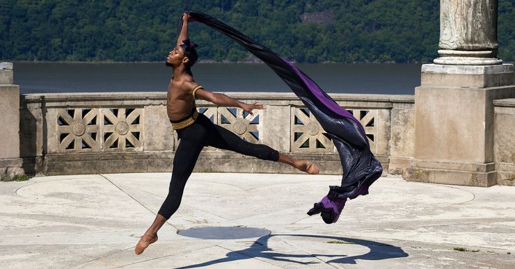 Khayr Muhammad leaps in the air with a cape in his right hand, streaming behind him.