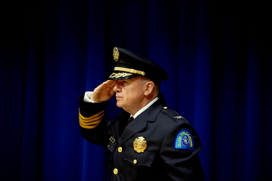 A White police officer in uniform salutes in profile.