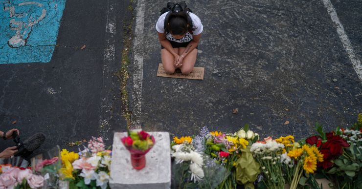 A women kneels in front of a memorial at Gold Spa, one of three Atlanta-area spas targeted in a mass shooting that killed eight people, on March 18, 2021.