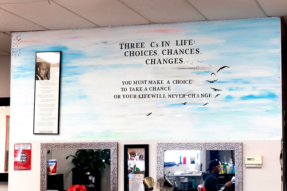 A mural inside a barbershop reads, “Three C’s in Life: Choices, chances, changes. You must make a choice to take a chance or your life will never change.”