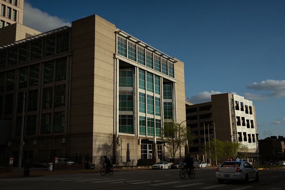 A photo shows a gray jail building with blue windowpanes. 