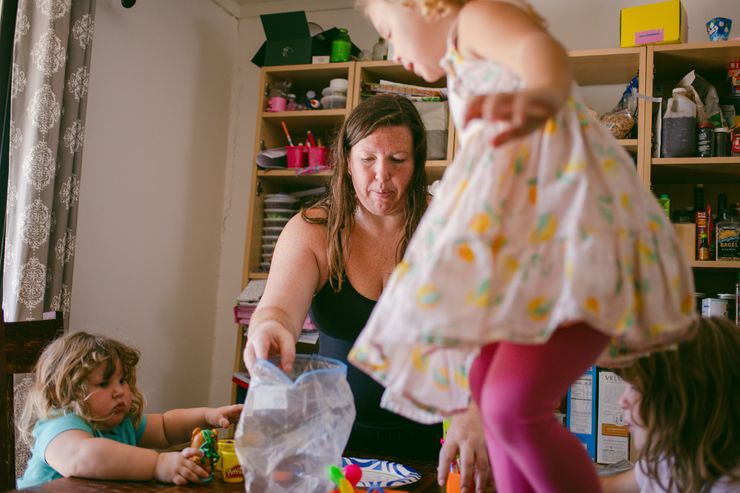 Susan Horton, a White woman wearing a black tank top, arranges her children’s toys on top of a table.