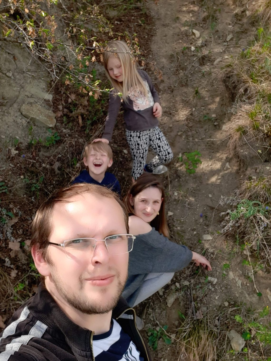 A photo shows a White man smiling at the camera with his wife and two children. 