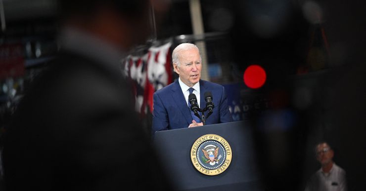 President Joe Biden, a white male in a navy blue suit, delivering a speech at a podium with the seal of the President of the United States. 