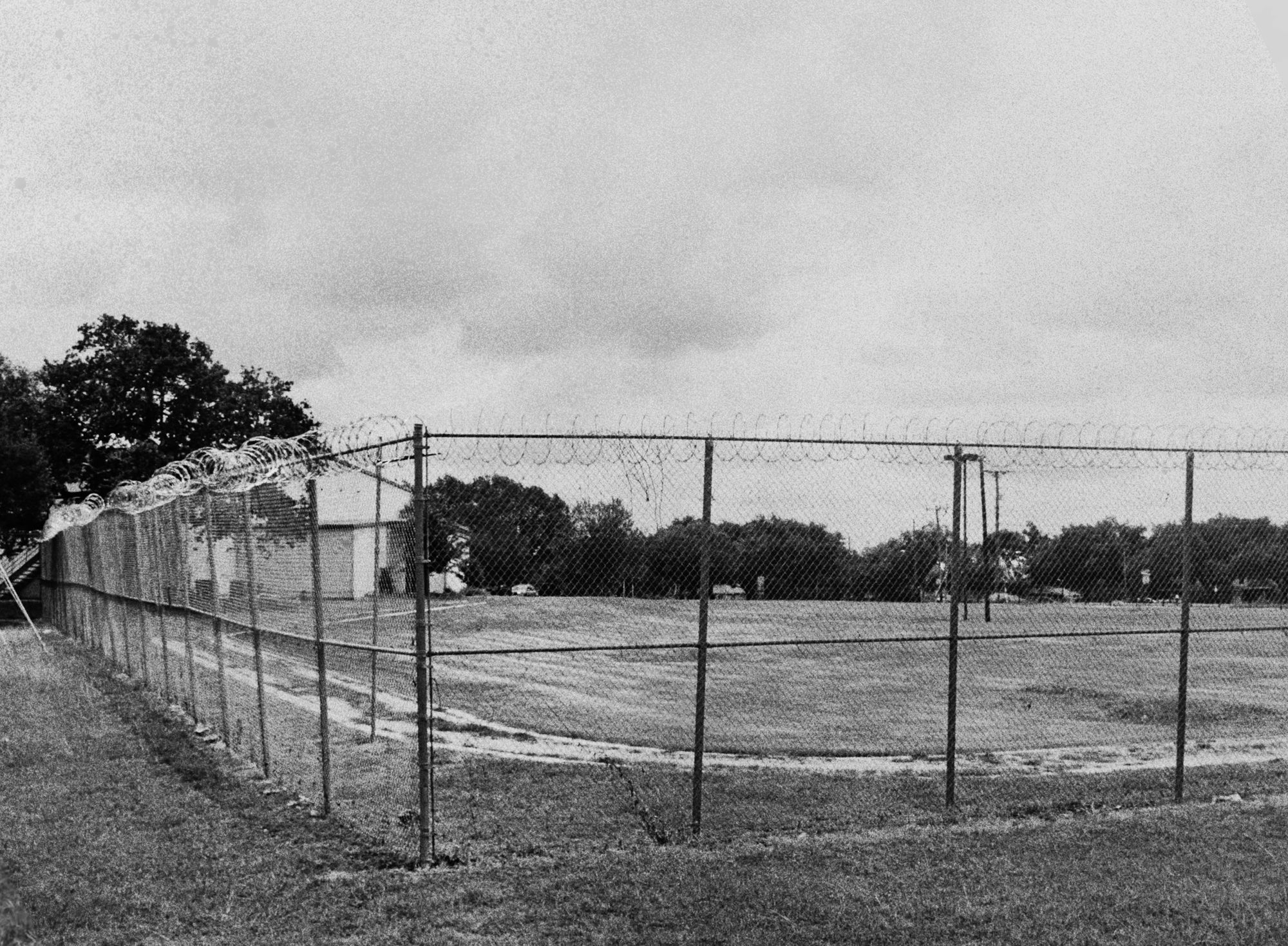A photo shows a grassy field with barbed wire fencing around it. 