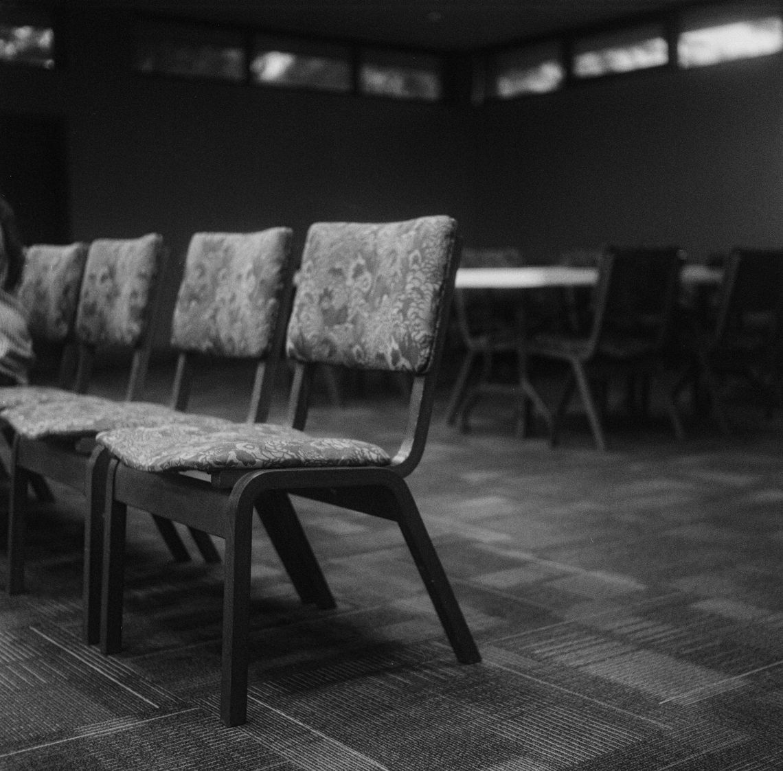 From left to right, black-and-white photos show a row of patterned chairs with wooden legs in a carpeted room, rows of bookshelves in a library, and two book drop boxes outside a library. 