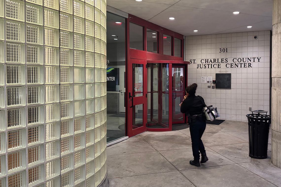 A woman in black clothing walks toward the entrance of a building with a sign that reads, “St. Charles County Justice Center. 