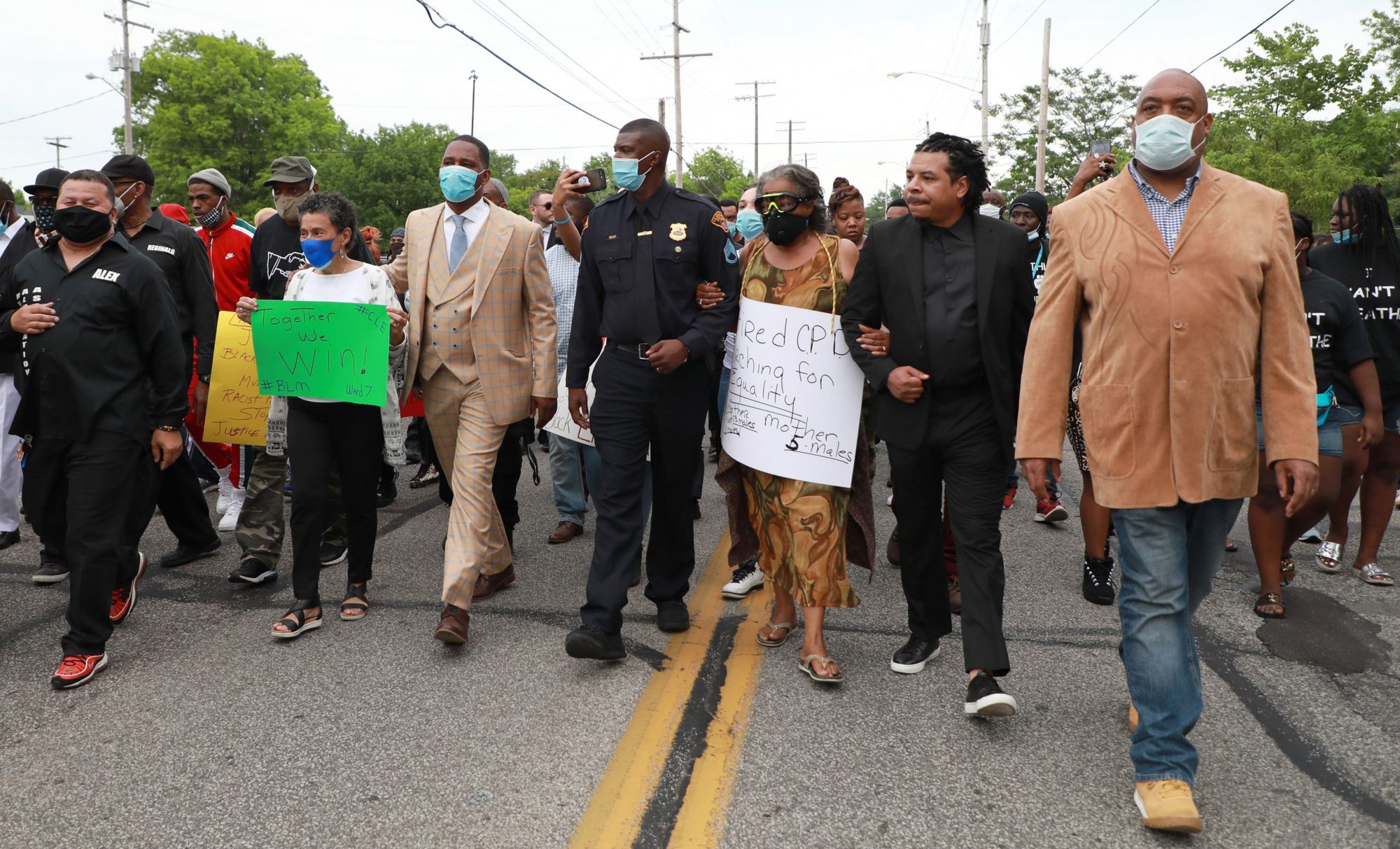 Vincent Montague, a Black police officer wearing his uniform, marches with the group. 
