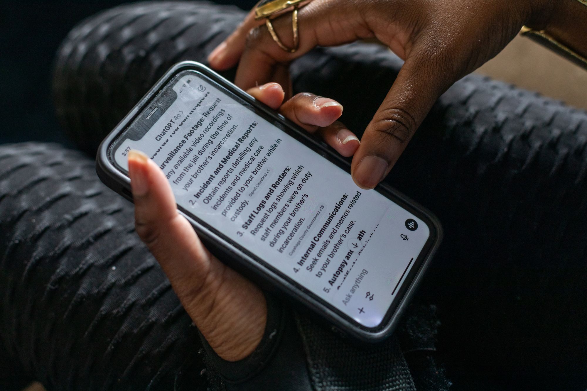 A close-up photo of a Black woman’s hands holding a smartphone displaying text results from ChatGPT. 
