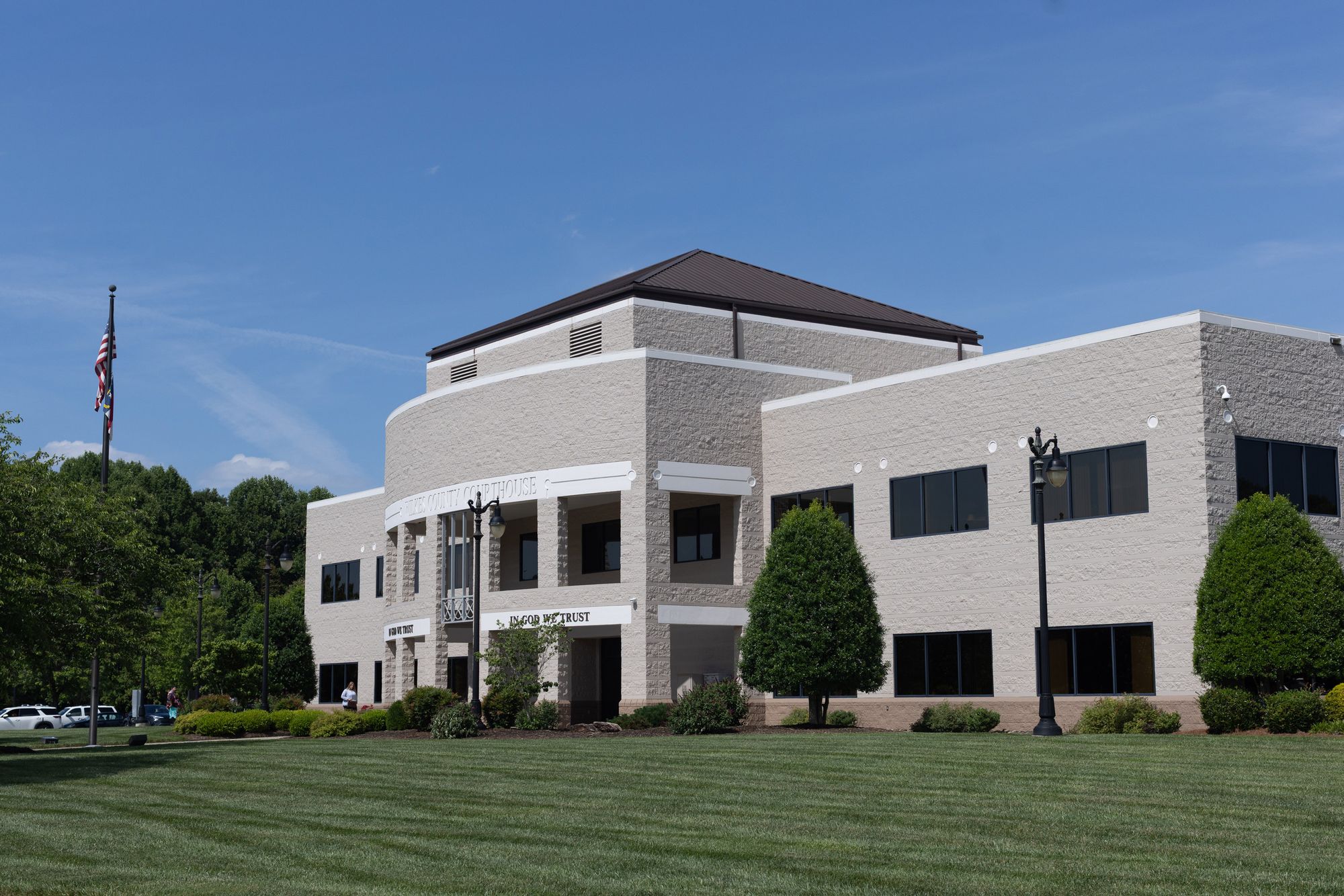 A photo of a beige, two-story building with a green lawn, under a blue sky with a few clouds.