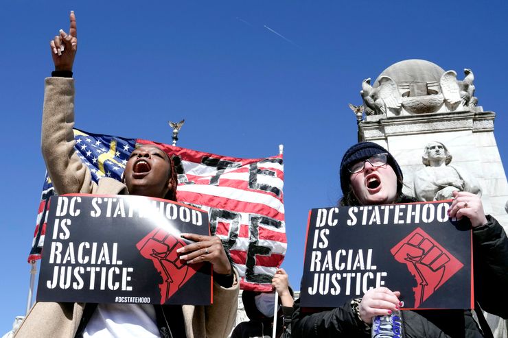 A Black woman and a White woman carried signs reading "DC Statehood is racial justice" during a protest. 