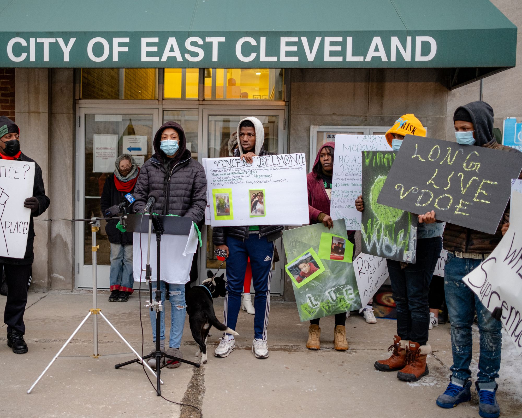 A photo of people holding signs with photos and phrases like “Long Live VDOE” in front of a podium.