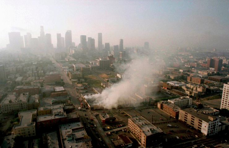 Smoke rises from a shopping center burned by rioters early Thursday morning April 30, 1992 as the Los Angeles skyline is partially obscured by smoke. More than 300 fires were reportedly set after four police officers were acquitted Wednesday of the beating of motorist Rodney King. (AP Photo/Paul Sakuma)