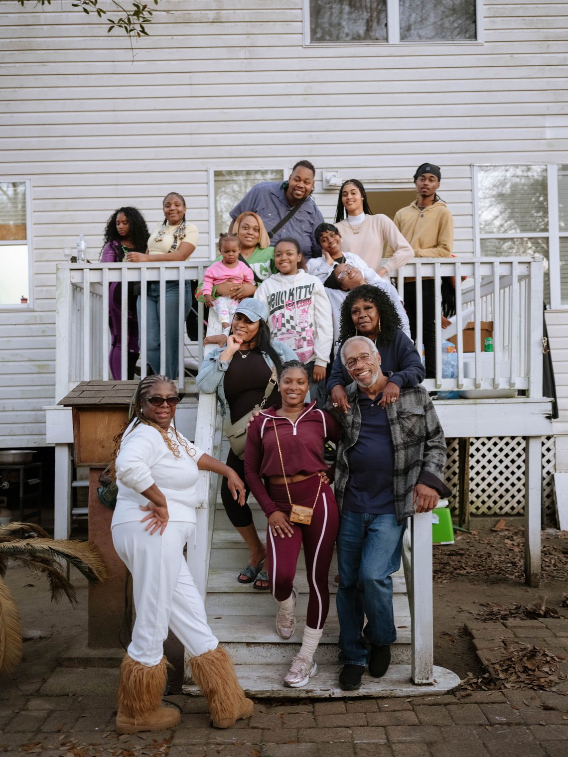 A group picture shows Moses, Armour, and her smiling family and friends standing on a deck and the deck stairs. 