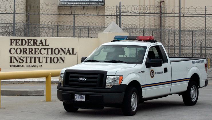 A guard drives past the entrance of the Federal Correctional Institution, Terminal Island in California.