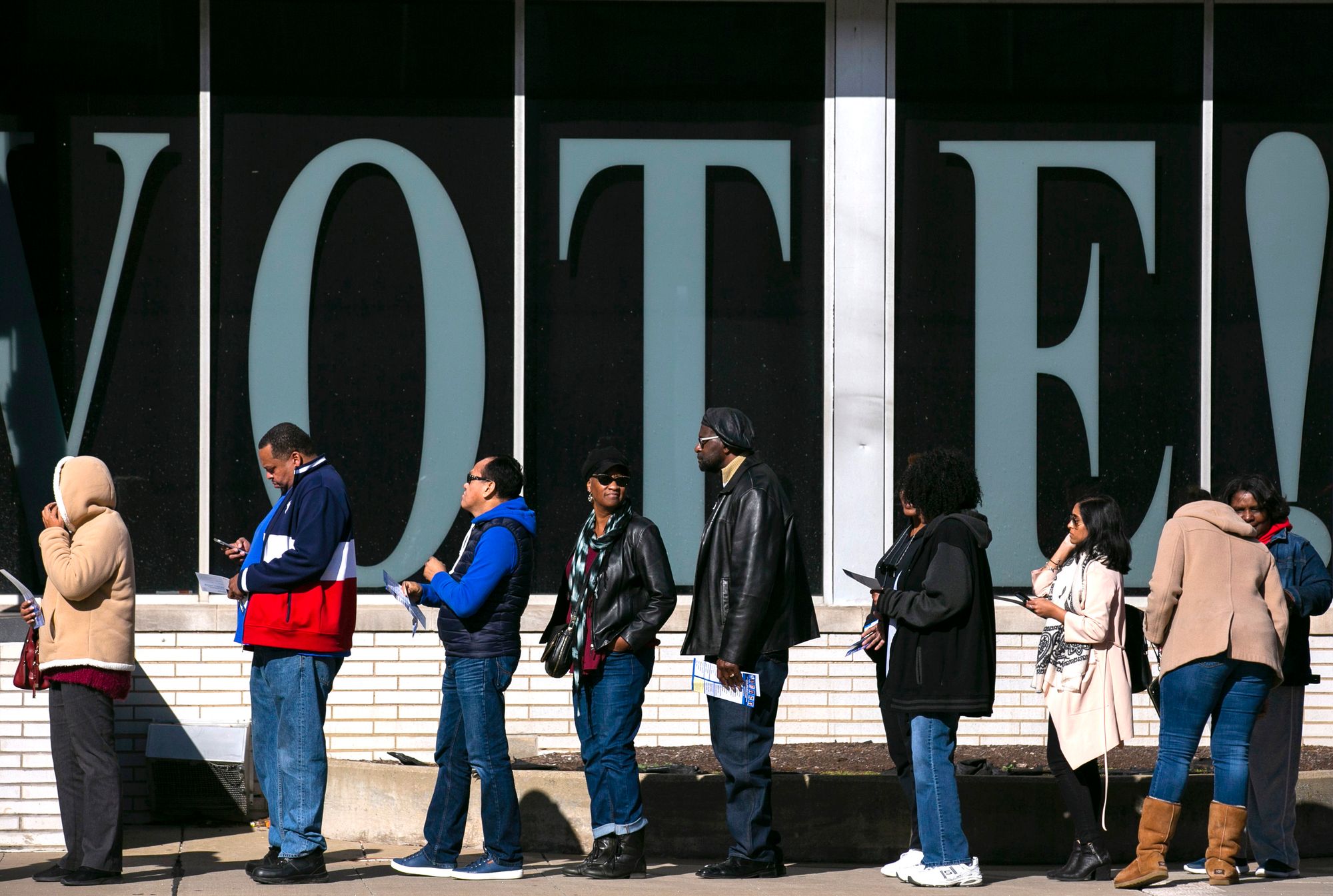 People are lined up outside the Cuyahoga County Board of Elections, wearing winter clothing, waiting to vote.  