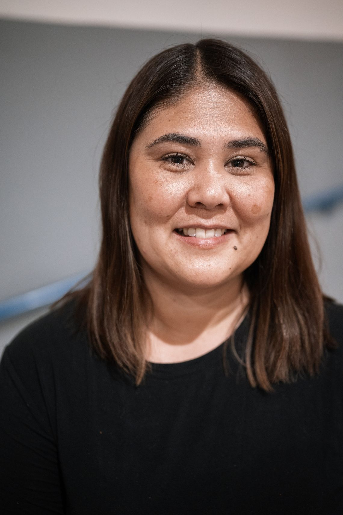 A photo shows a light-skinned woman with dark brown hair smiling at the camera. 