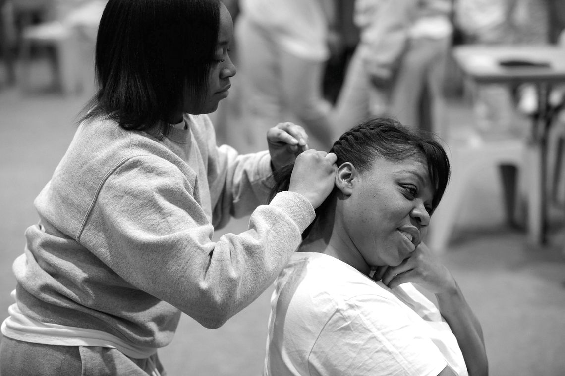 Jamille braided Latashia’s hair as they wait for the bus of children to visit Logan Correctional Center. 