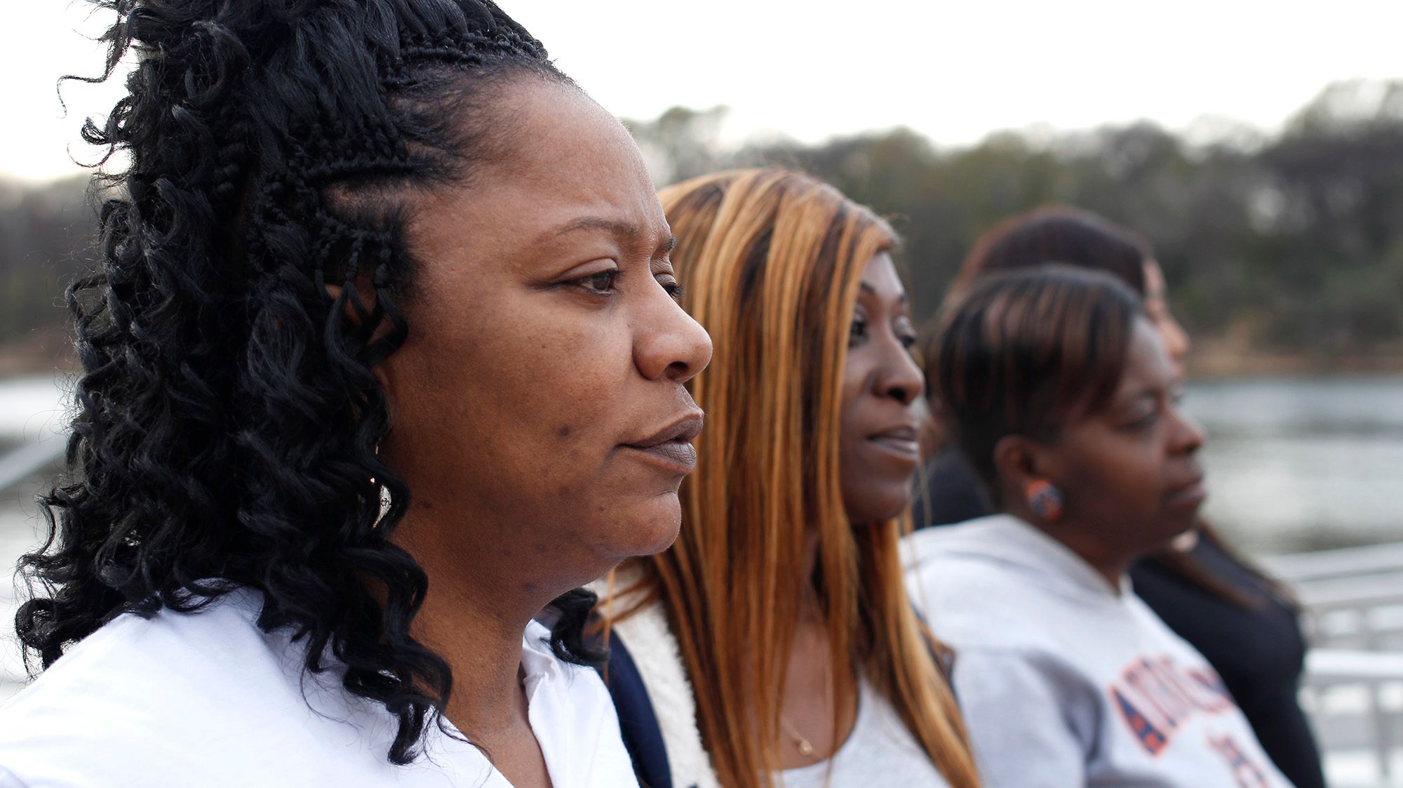 Three Black women looking pensive toward the right. 
