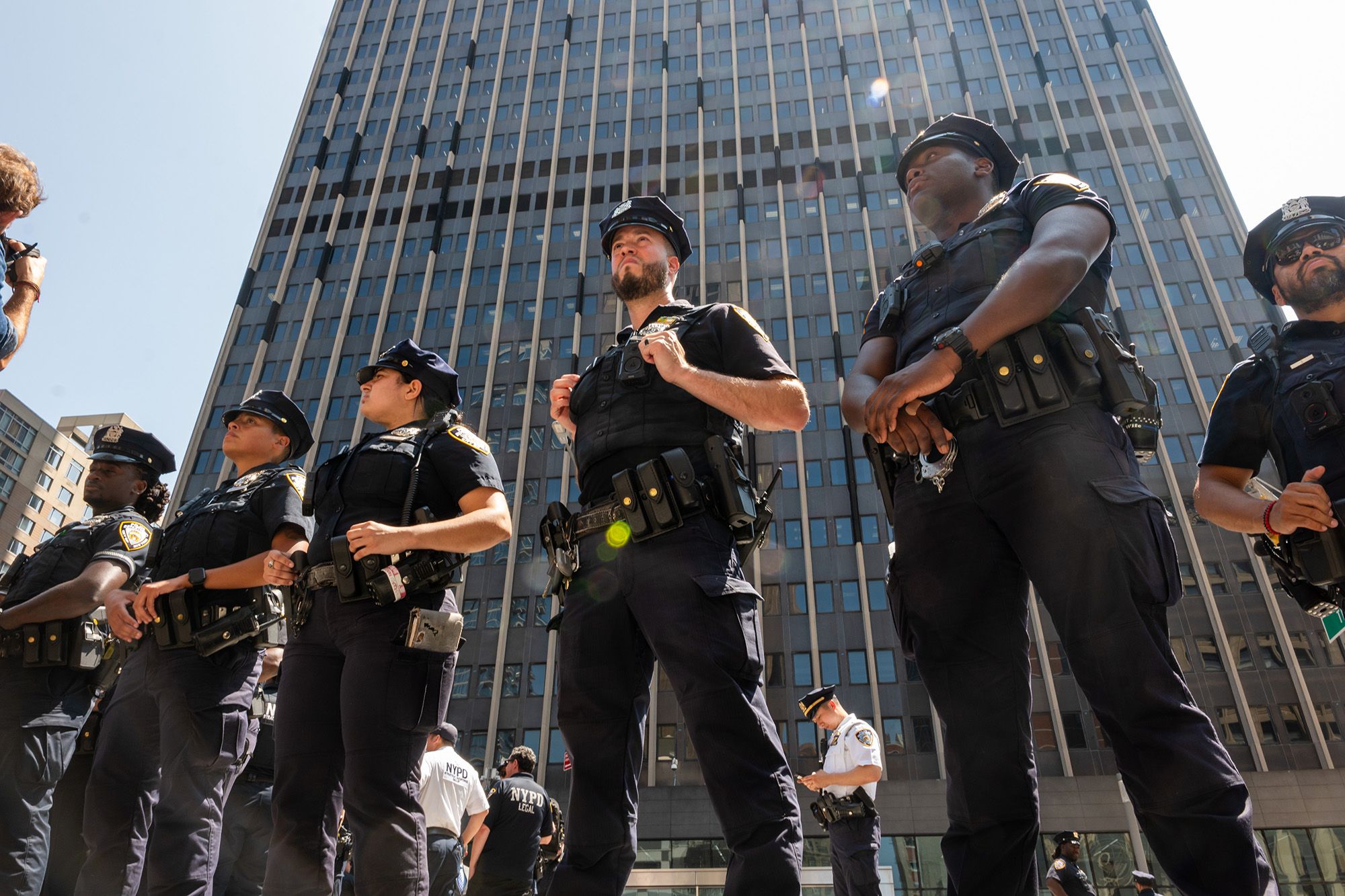 A photo shows a group of New York police officers in uniform stand in a line outdoors. 