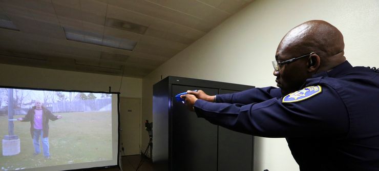 Lt. Sekou Millington of the Oakland Police Department uses his taser to respond to a video scenario of a man wielding a knife.