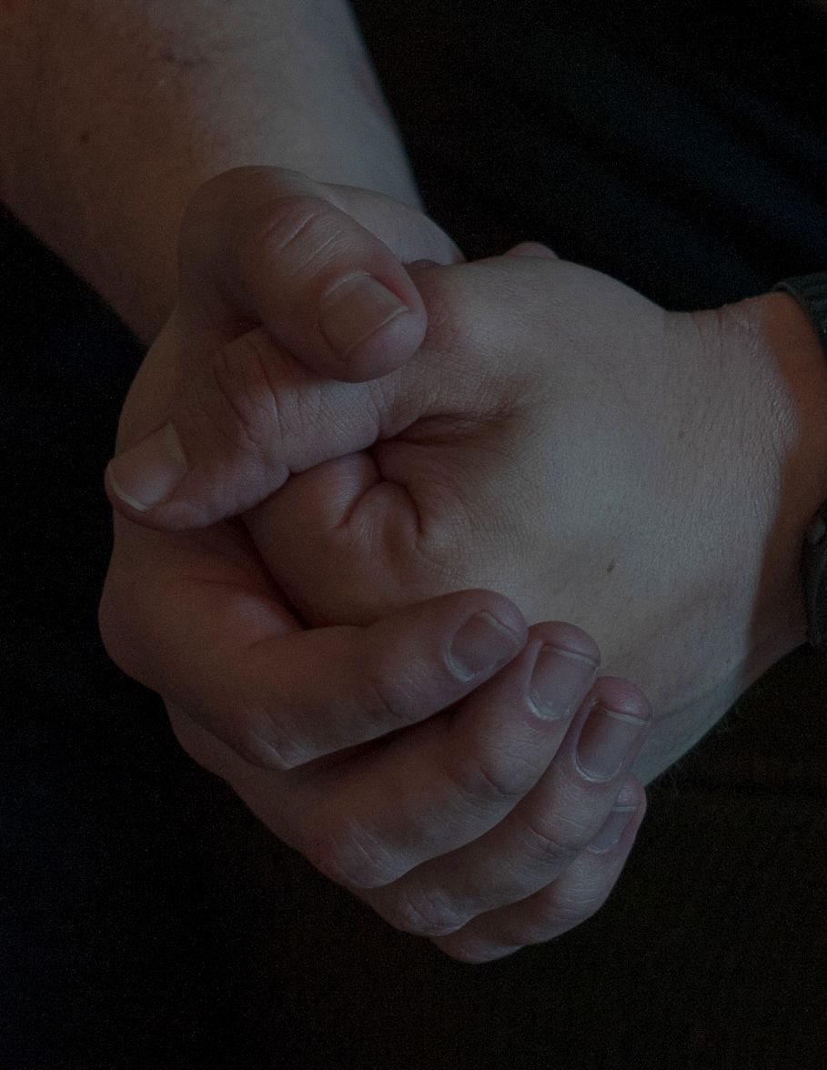 A White man’s hands are clasped together.