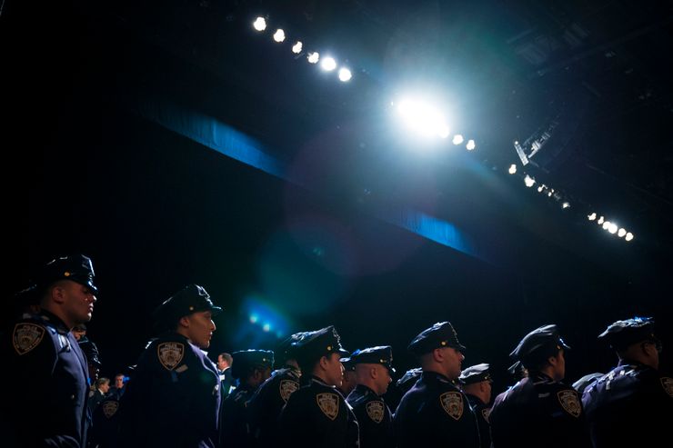 New York police officers are lined up inside an auditorium. 