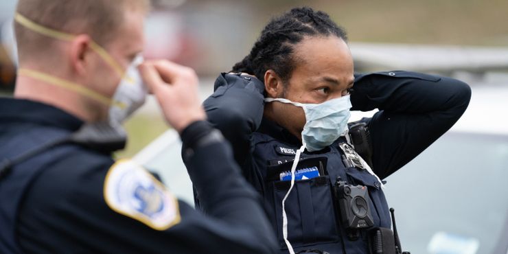 Metropolitan Police Department officers put on face masks before removing a handcuffed detainee from a police cruiser at the United Medical Center in Washington, D.C. on Monday. 