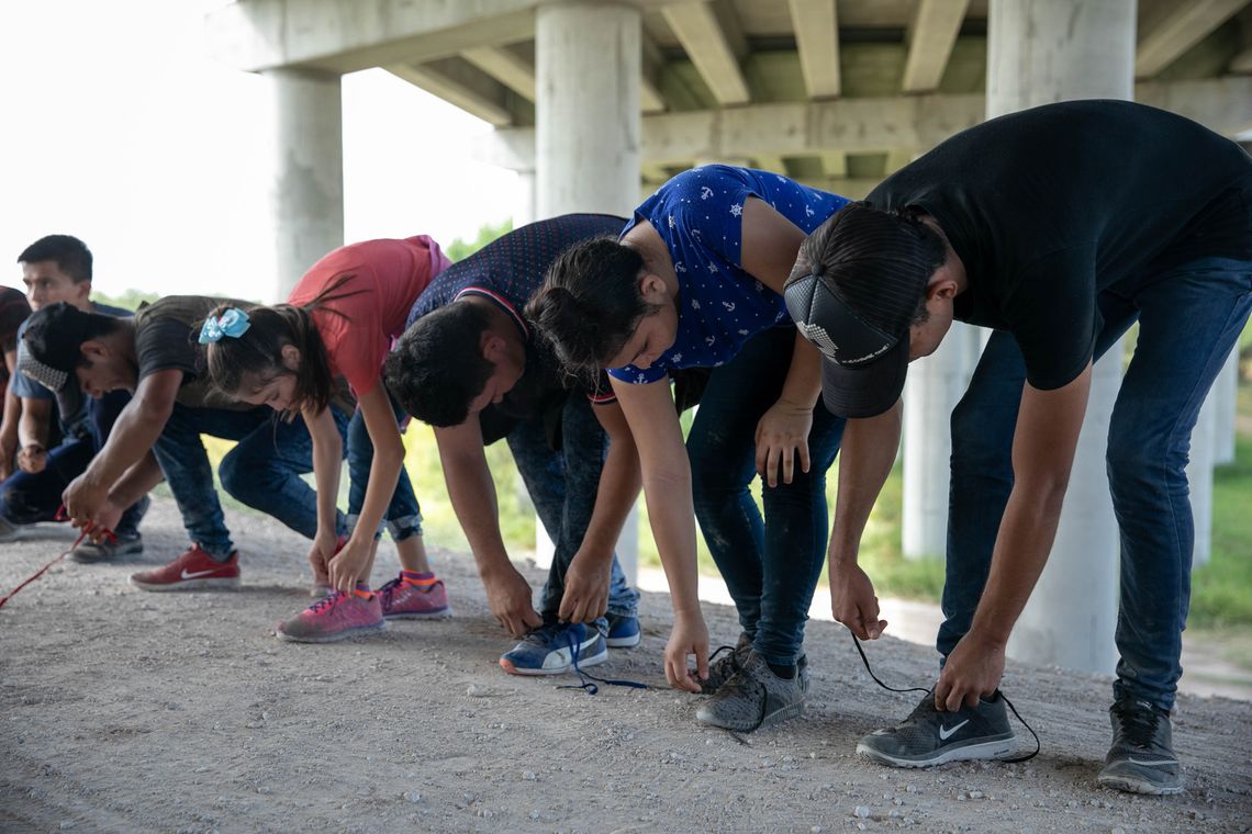 Migrants remove their shoelaces as a security measure after being taken into custody by the Border Patrol near Mission.