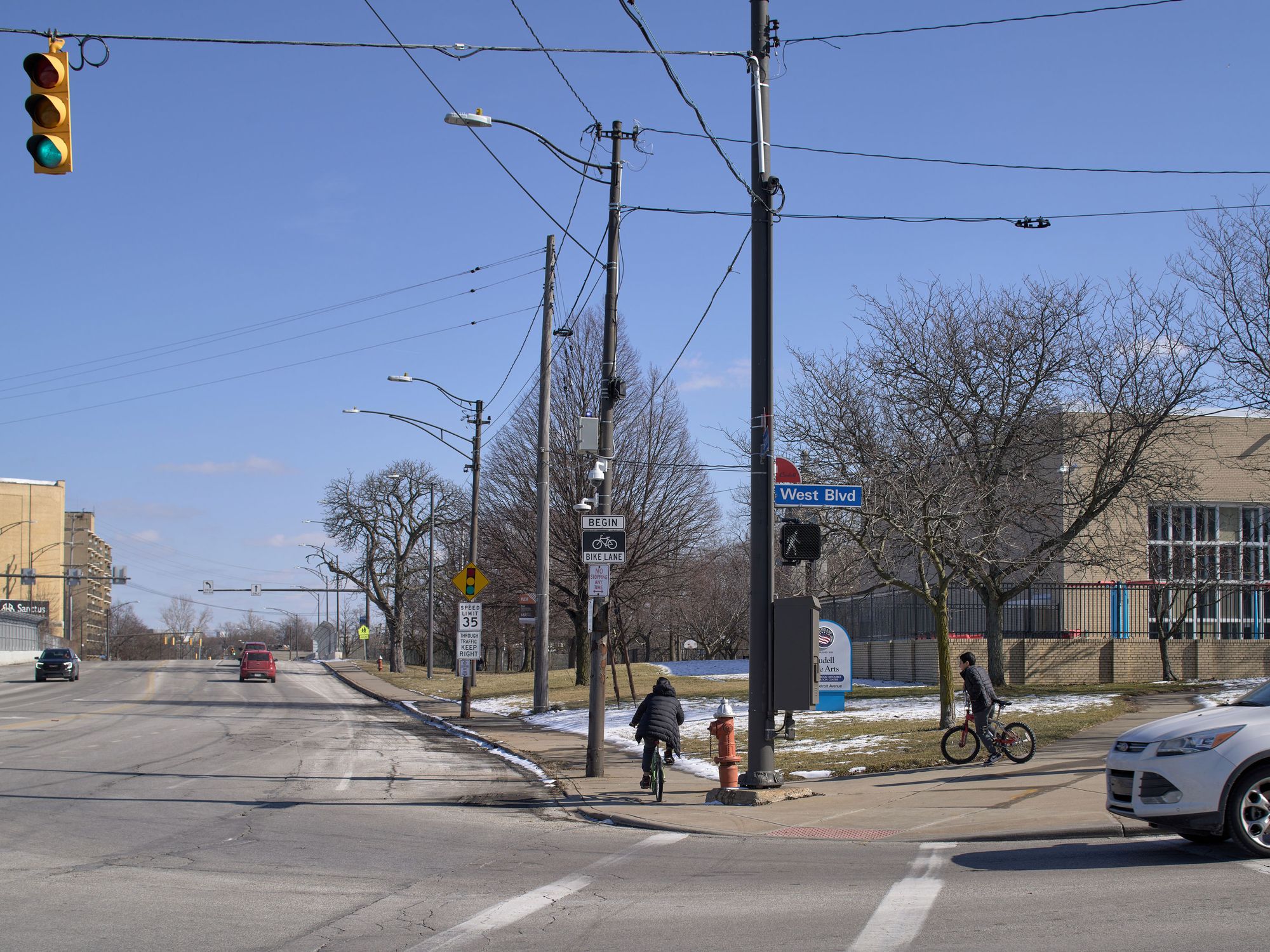 A photograph of two children riding bikes past surveillance cameras mounted near a recreation center. 