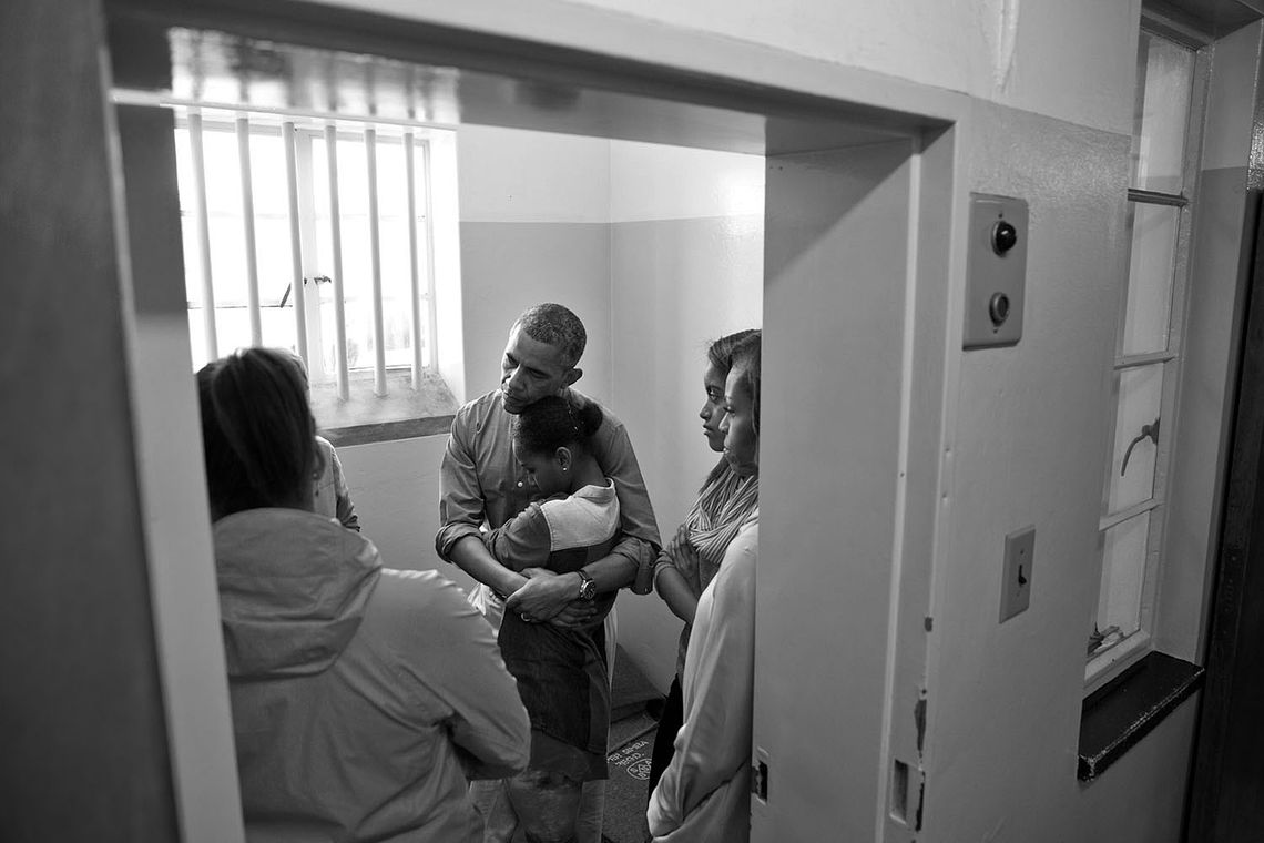 Inside Nelson Mandela’s former prison cell, President Barack Obama embraces his daughter Sasha while listening to Ahmed Kathrada recount his years spent imprisoned on Robben Island in Cape Town, South Africa in June 2013. 