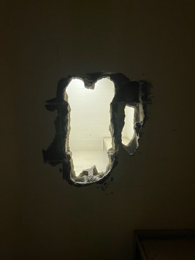 A photo shows a large hole in the wall of a cell. 