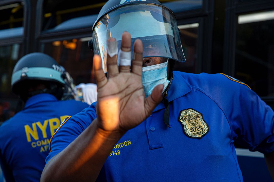 An officer stands in front of other police who are arresting two women for spray painting a bus in Brooklyn.