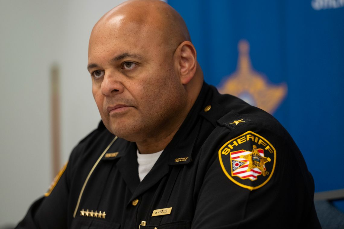 Cuyahoga County Sheriff Harold Pretel, a bald man with medium-toned skin, wears a black uniform with a sheriff’s patch on his left shoulder. 