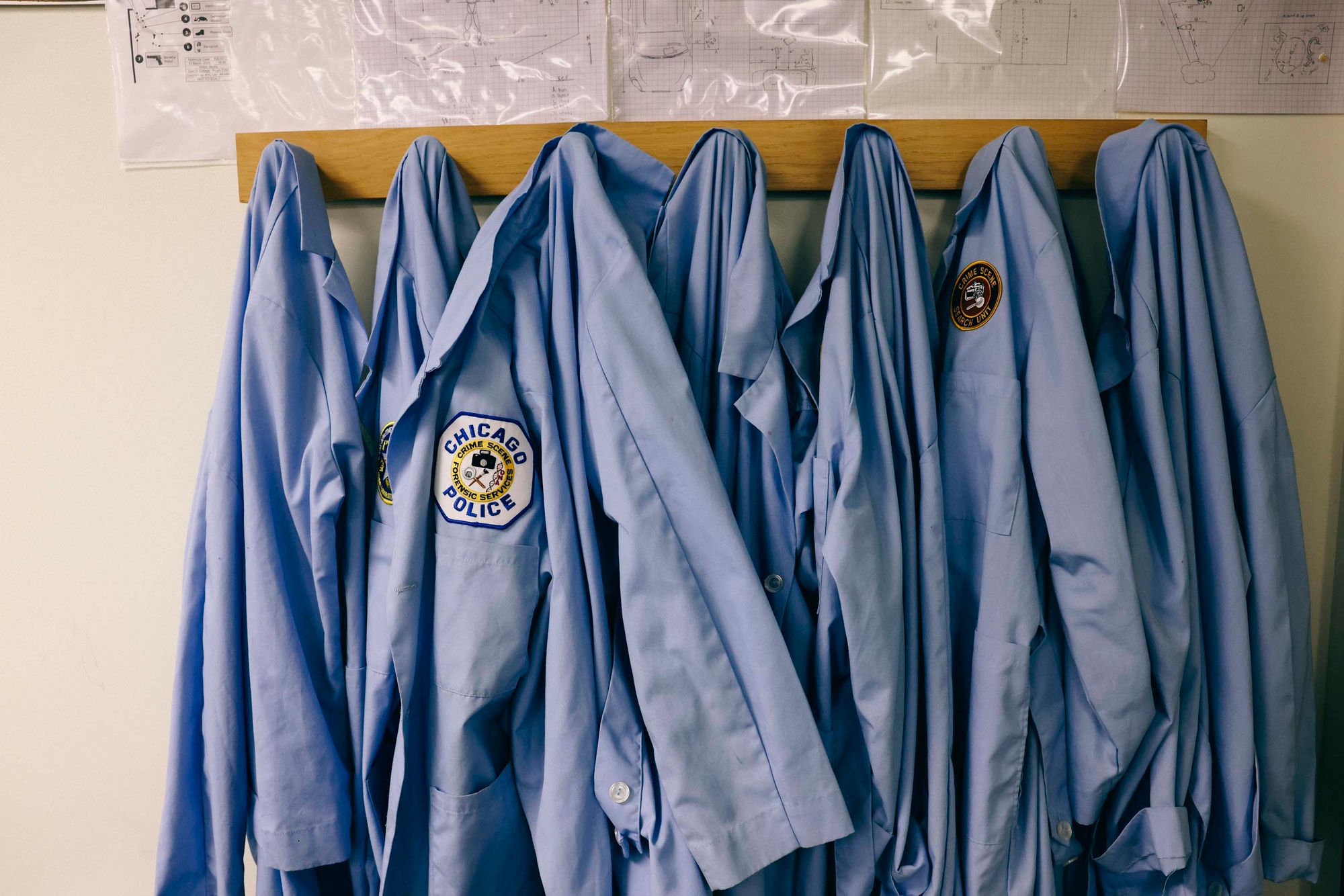 A photo shows seven blue short-sleeved button-down shirts hanging from a wall-mounted coat rack.