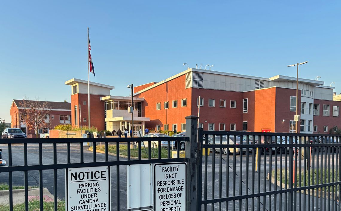 A photo of a brick building behind a black fence. 