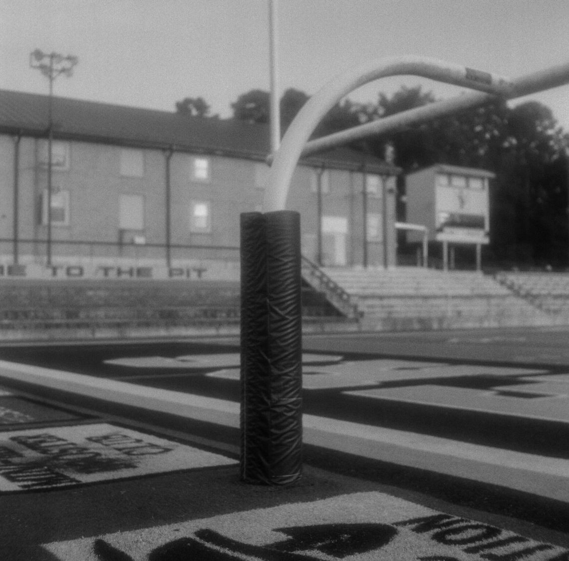 A black-and-white photo of a padded goalpost on a football field. D