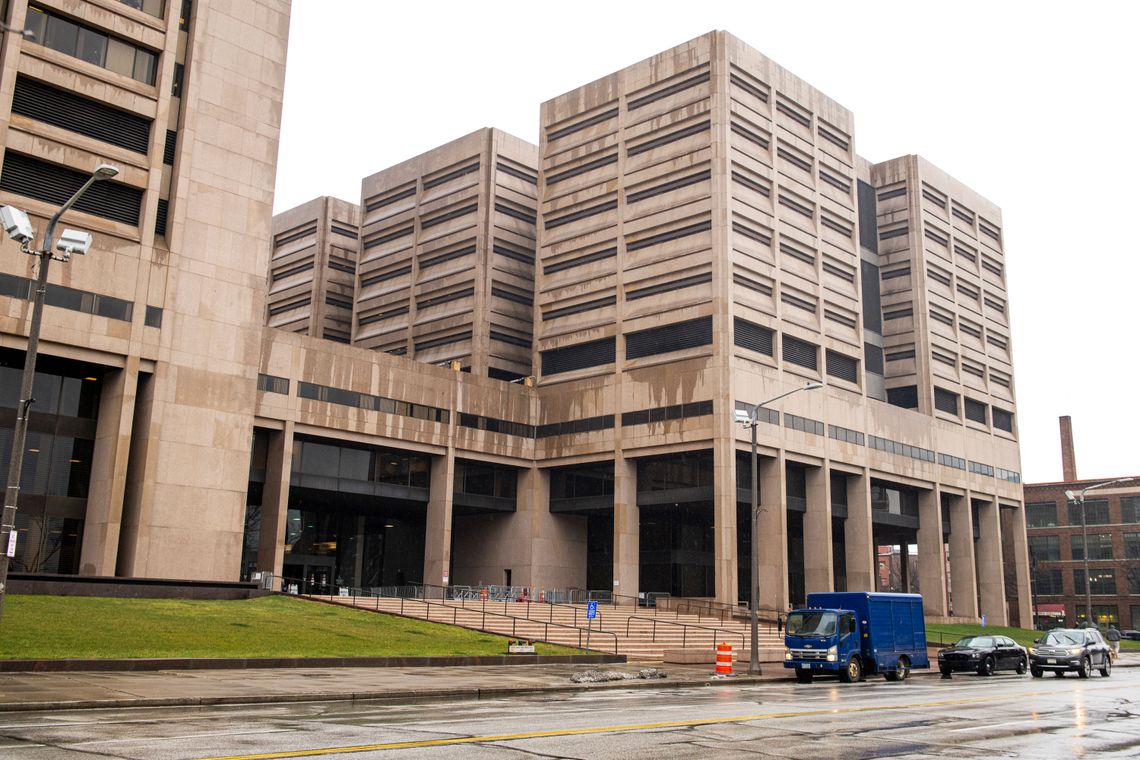 The exterior of the Cuyahoga County Jail, a beige multistory building with narrow, rectangular windows, on a rainy day. 