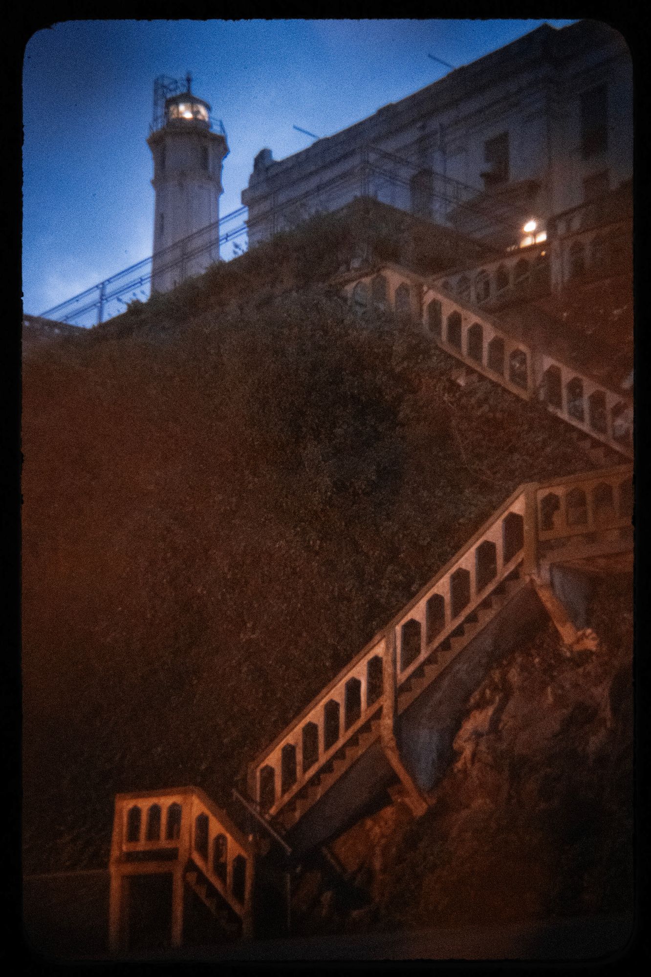 A photo shows stairs leading up to a building at Alcatraz. The photo has a vignette effect. 