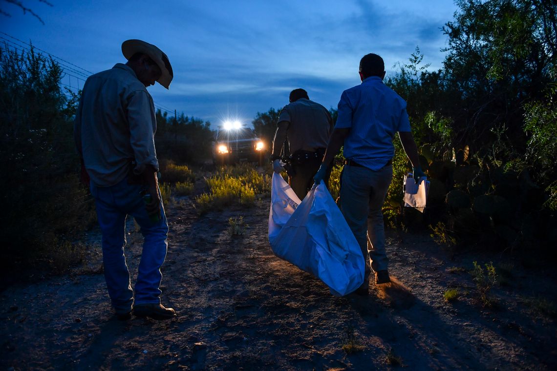 Ranch hand Juan Ramirez, left, looks on as Webb County Sheriff's Deputy Mauro Lopez, front, and Webb County Medical Examiner's Office investigator, Max Cantu, right, carry away the remains of a border crosser from a Laredo, Texas ranch, in 2016. 