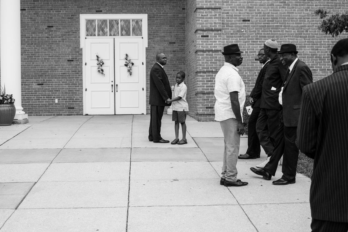 A young boy holds his father’s hand at the funeral for 16-year-old Alexander Kamara on July 21, 2012. 