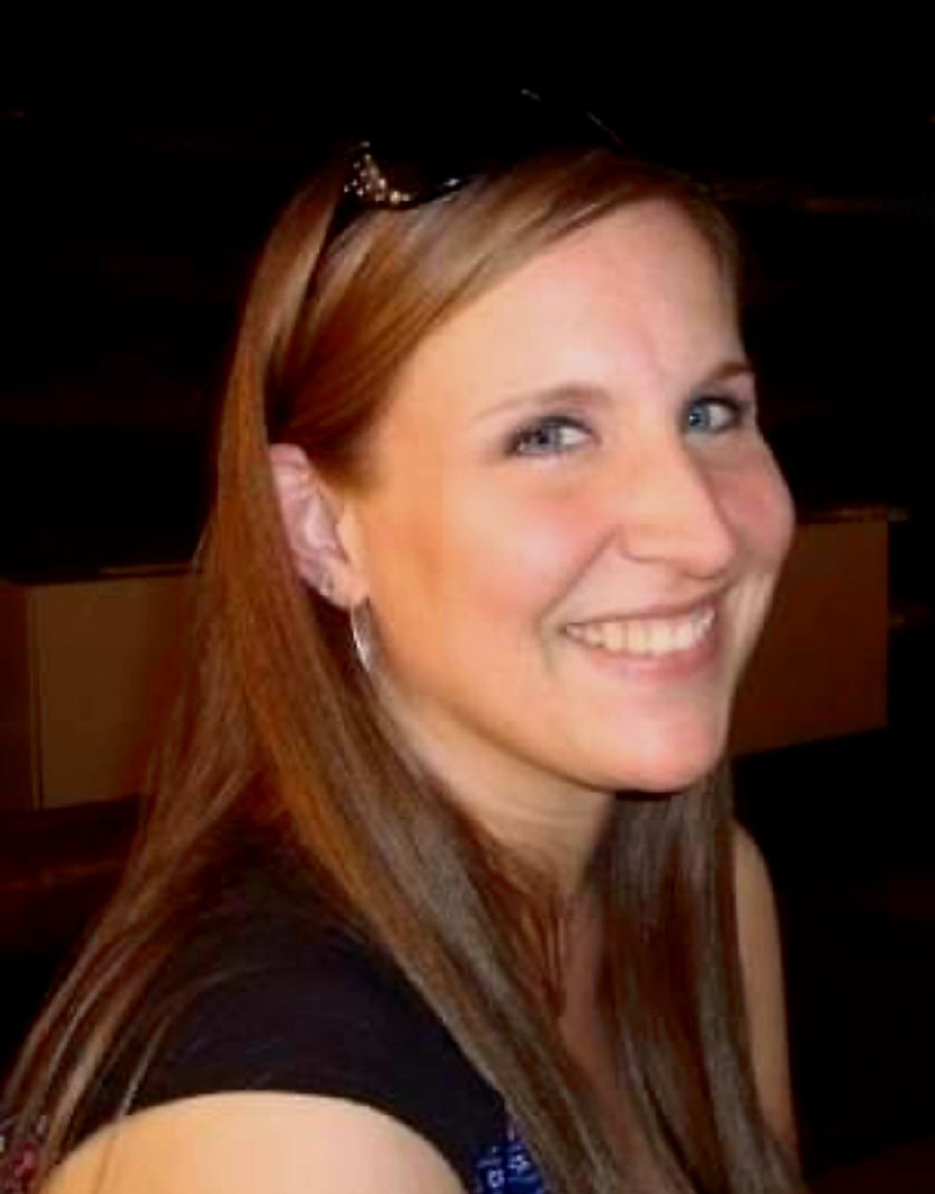 A White woman with long brown hair looks at the camera. 