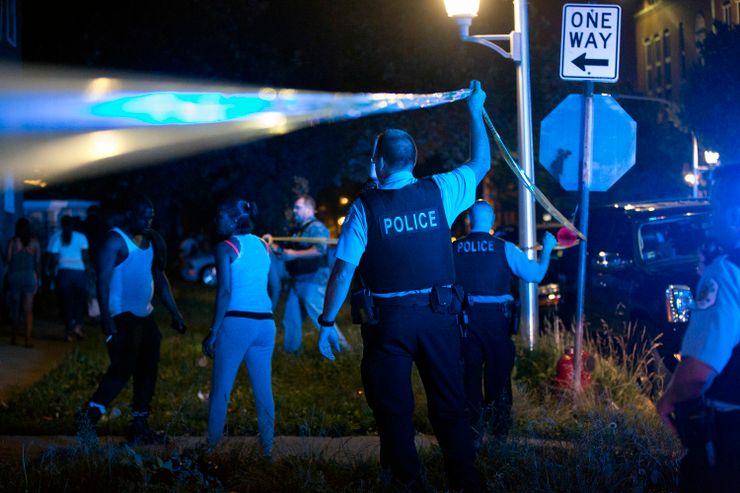 Members of the Chicago Police Department put up tape and clear the scene of a fatal shooting in June in the city’s East Garfield Park neighborhood.
