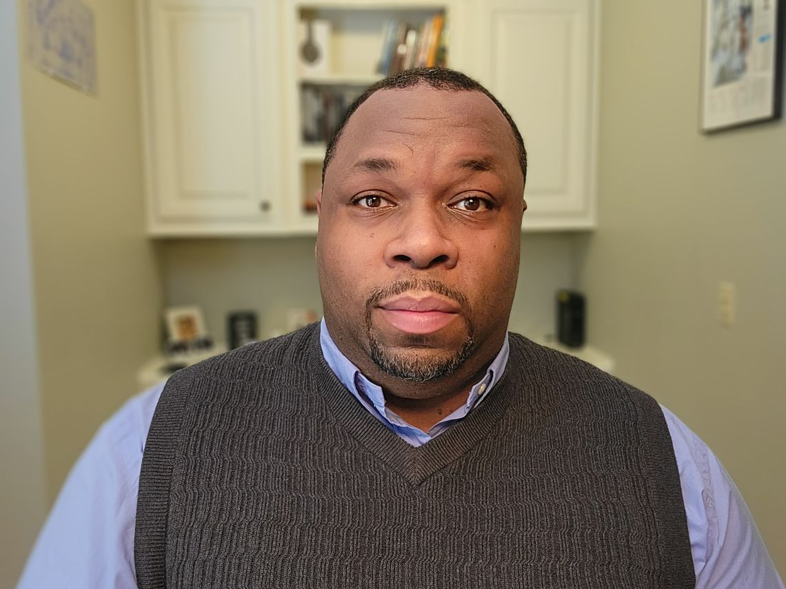 A portrait of Marlon Walker, wearing a blue dress shirt and gray vest. 
