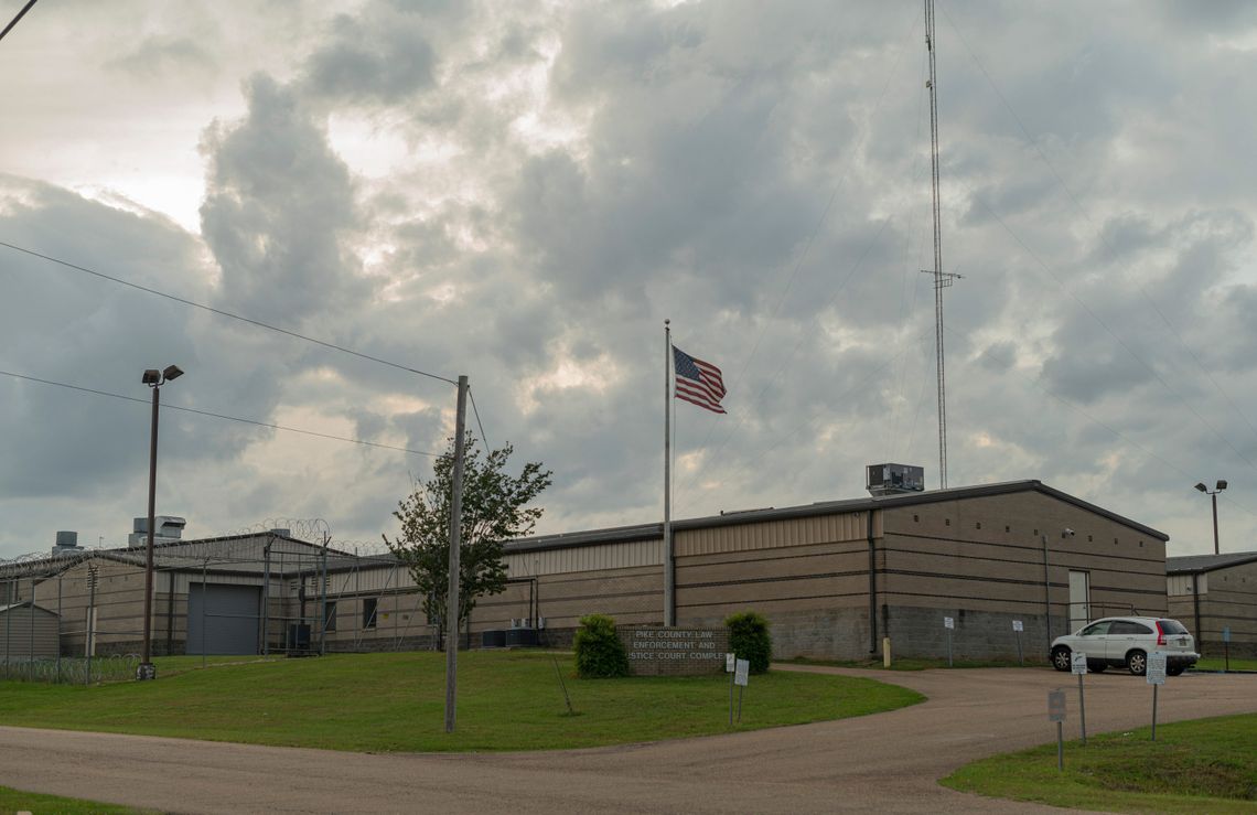 A photo of the exterior of a jail building on an overcast day. A sign by an American flag outside the building reads: “Pike County Law Enforcement and Justice Court Complex.”