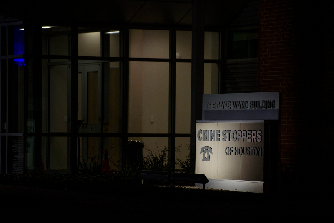 A sign in front of the exterior of the Crime Stoppers office building is lit up at night. 