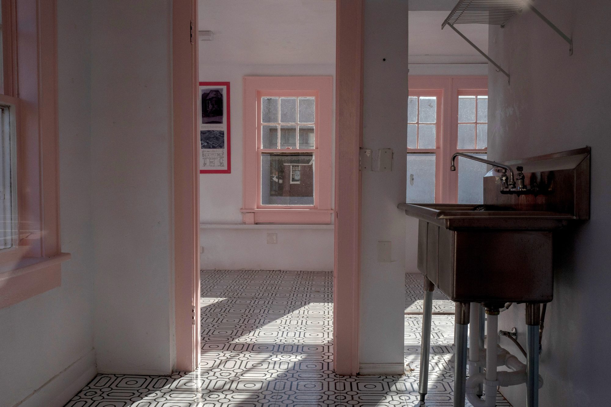 The photo shows the inside of the Cookie Cottage, a sink in the shadows on the right and light coming into two empty rooms.