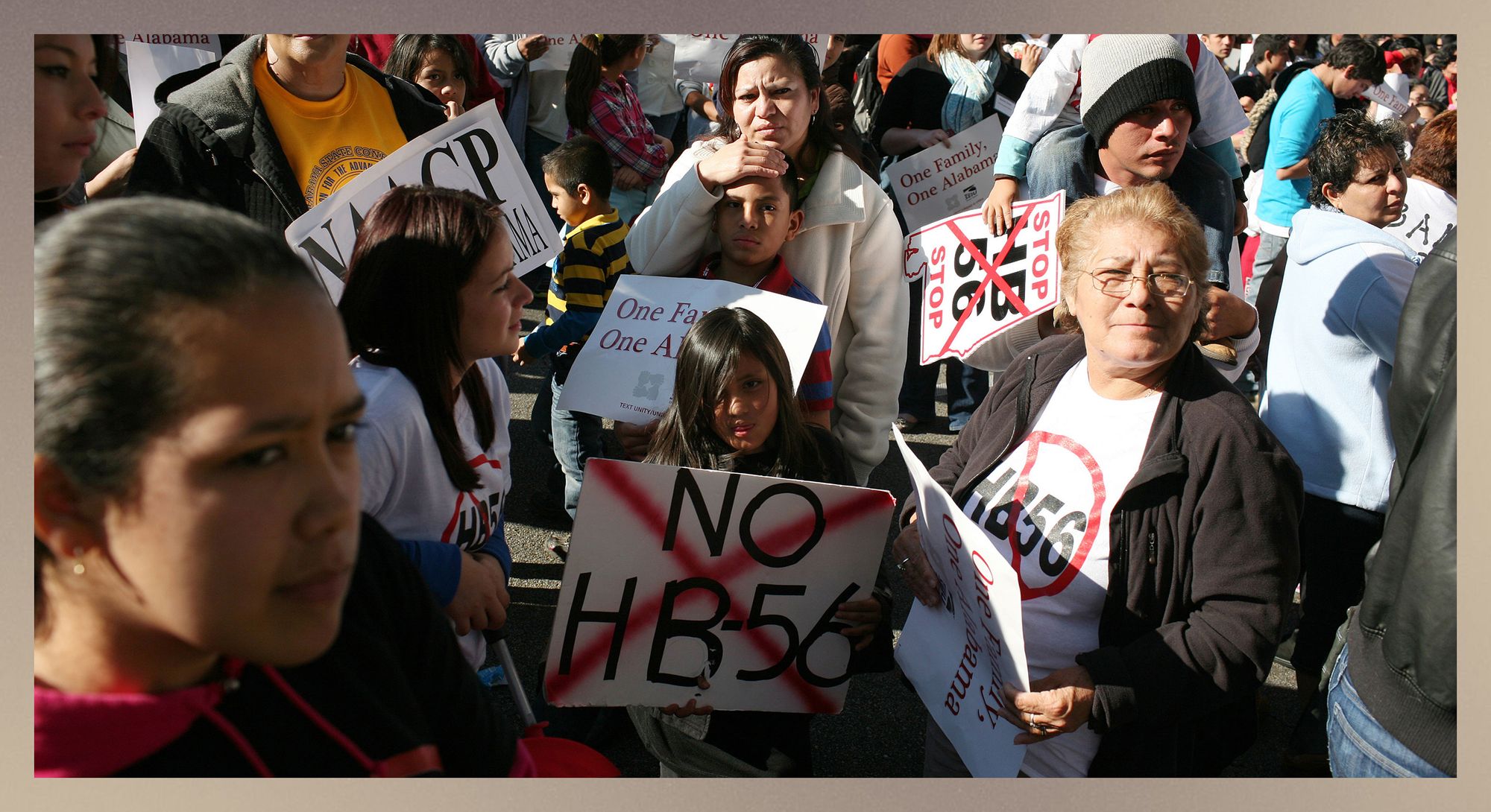 A photo shows a crowd of mostly Latino people of different ages holding signs and wearing shirts against HB-56. 