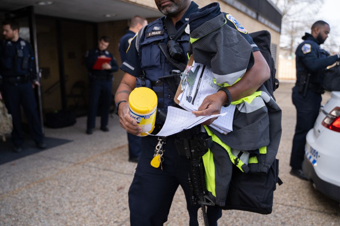 Officer Steven Prade carried a container of Lysol wipes in one hand, his department-issued M4 assault rifle in the other, outside the Fifth District Metropolitan Police Department building on Monday. 