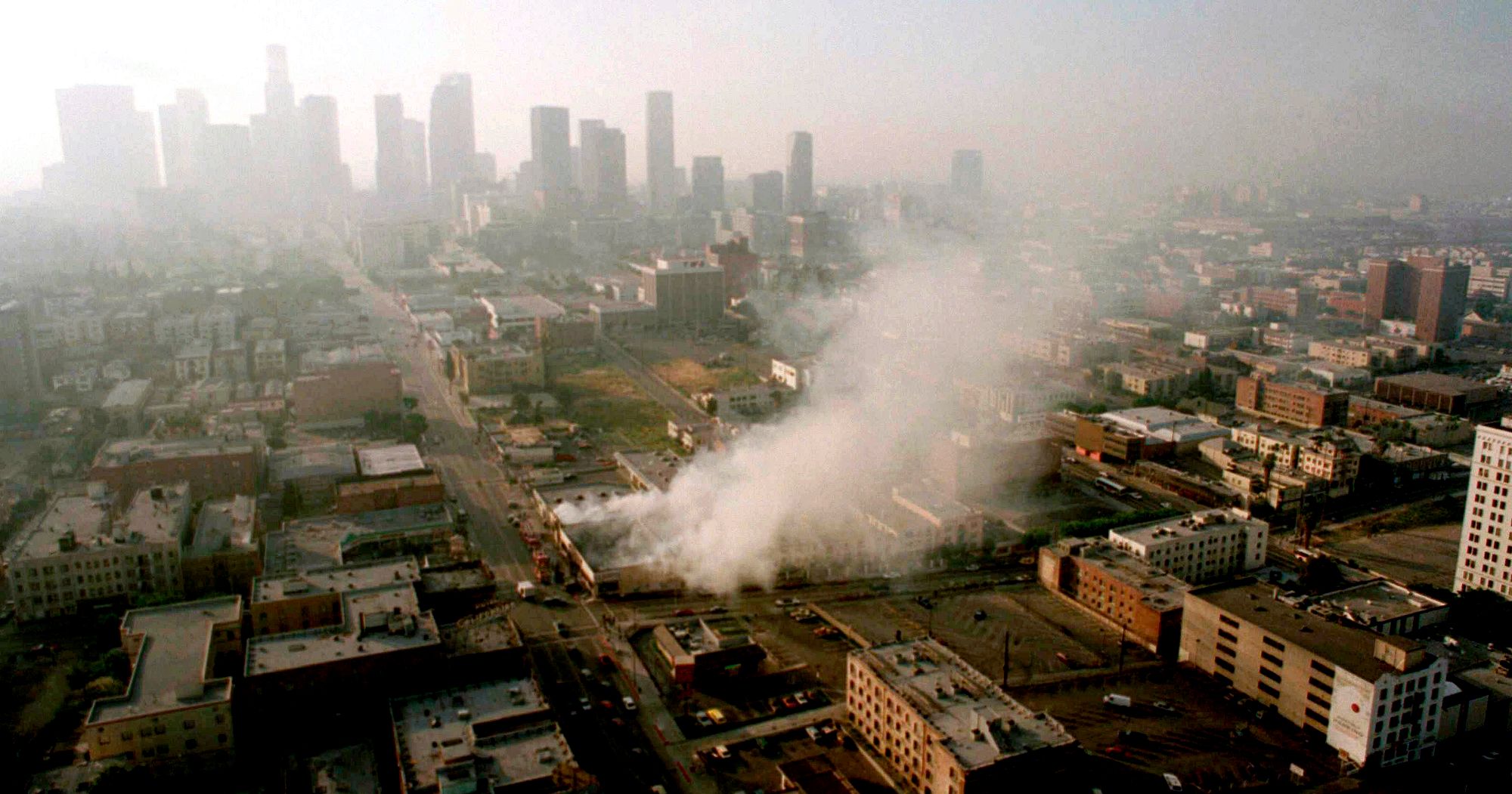 Smoke rises from a shopping center burned by rioters early Thursday morning Apr. 30, 1992 as the Los Angeles skyline is partially obscured by smoke.